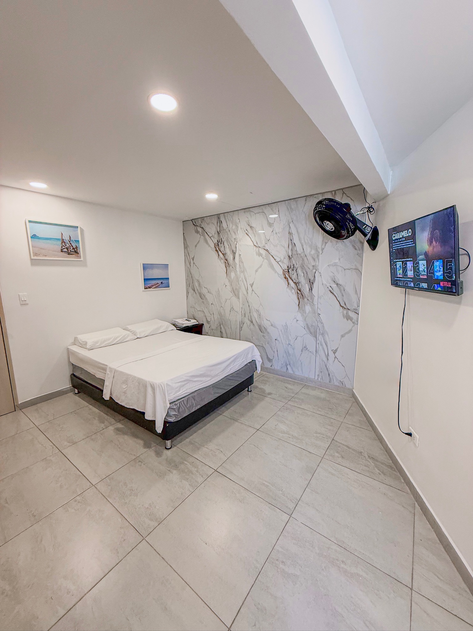 Habitación Doble Delux en Luiggis Home Cúcuta — cama doble con pared de mármol y TV