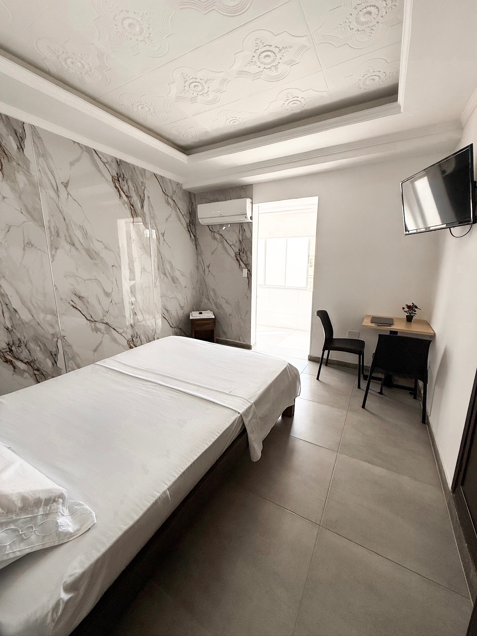 Habitación Doble en Luiggis Home Cúcuta — cama doble con pared de mármol, TV y escritorio